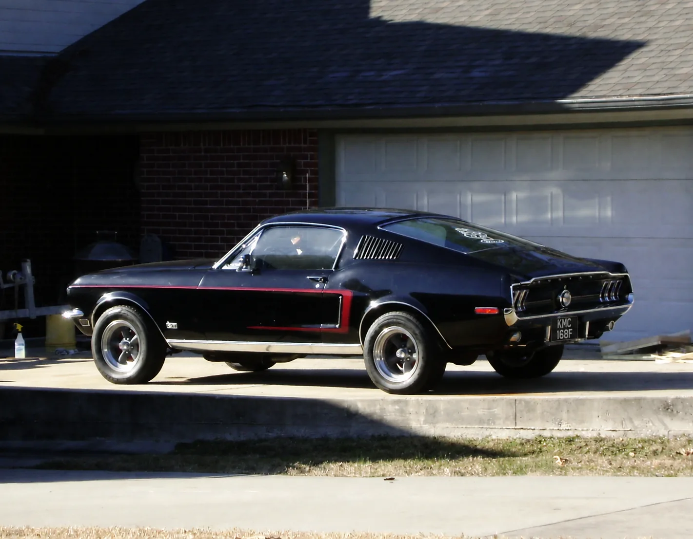 Black 1968 Ford Mustang Fastback parked on a quiet driveway with a UK-style registration plate